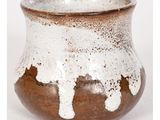 un vase brun et blanc posé sur une surface blanche