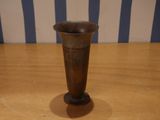 a small metal vase sitting on a wooden table