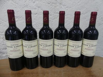 six bouteilles de vin rouge sont alignées sur une table en bois