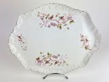 a white plate with pink flowers on it on a stand