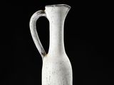 a white vase sitting on a table with a black background