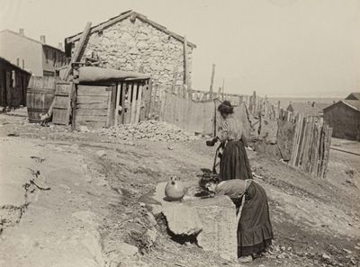 an old photo of a woman pouring water from a well