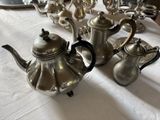 three silver teapots sitting on a white tablecloth