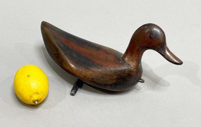 un canard en bois posé à côté d'un citron sur une table