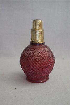 une petite bouteille en verre rouge avec un bouchon doré