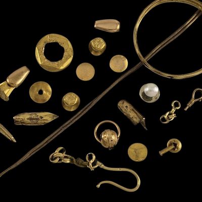 Plusieurs bijoux en or sont exposés sur un fond noir