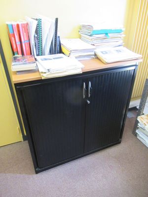 une armoire noire sur laquelle sont posés des livres, dans une pièce