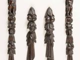 four carved wooden spoons are lined up on a white surface