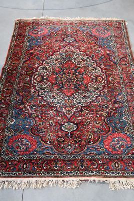 un grand tapis persan orné d'un motif en médaillon sur fond bleu