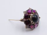 a close up of a purple and black stone ring on a white surface