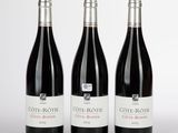 trois bouteilles de vin rouge posées sur une table blanche