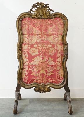 une chaise ancienne dont le dossier est recouvert d'un tissu rouge et or