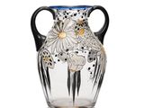 a glass vase with a black handle on a white surface
