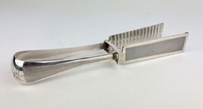 a silver plated comb with a handle on a white surface
