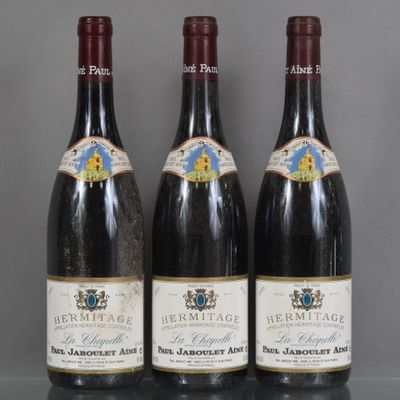 three bottles of wine are lined up on a glass table