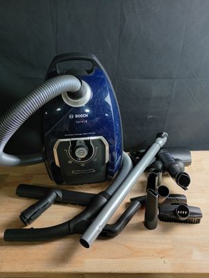 un aspirateur bleu et argent posé sur une table en bois