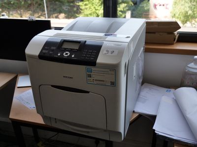 une imprimante posée sur un bureau devant une fenêtre
