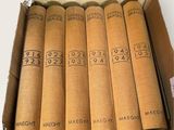 six books in a cardboard box on a white surface