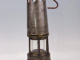 an old fashioned metal lantern with a metal handle on a white surface