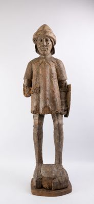 an old wooden statue of a boy with a hat and a bag