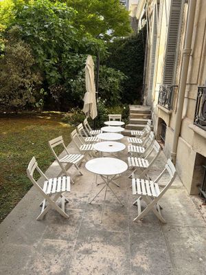 de nombreuses chaises et tables sur le trottoir devant un immeuble