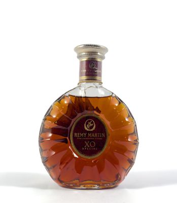 une photo d'une bouteille de brandy posée sur une surface blanche
