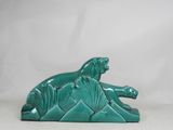 green ceramic sculpture of a lion laying down on a white background