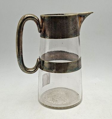 un pichet en verre muni d'une anse en métal, posé sur une table