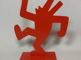 a red sculpture of a man on a skateboard on a white surface