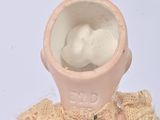 a small vase that has a doll inside of it