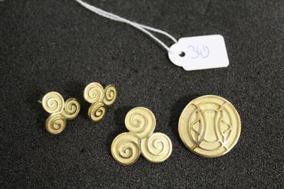 deux boutons en or et une pièce de monnaie avec une étiquette de prix sur un fond noir