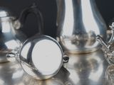 three silver teapots sitting on a silver table