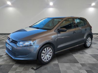 La Volkswagen Polo grise est garée dans une grande pièce au sol carrelé en damier.