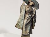statue d'une femme tenant un éventail, posée sur un socle dans une pièce