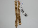 deux bracelets en or et une chaîne munie d'un fermoir, posés sur un fond blanc