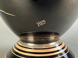 a black vase with gold stripes on it on a table