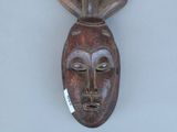 une image d'un masque en bois accroché au mur