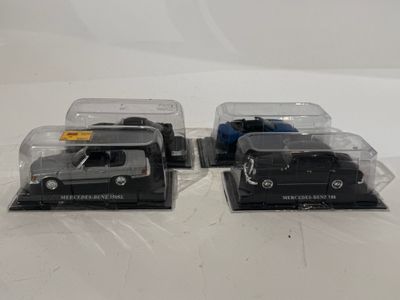 deux voitures noires moulées sous pression, présentées dans des boîtes en plastique transparent, posées sur une surface blanche