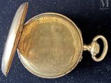 a close up of a gold pocket watch on a black surface