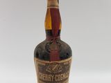 une vieille bouteille de whisky posée sur une surface blanche