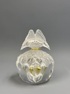 a clear glass perfume bottle with a bird on top of it
