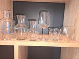 des bouteilles et des verres posés sur une étagère dans une pièce où se trouve un téléviseur