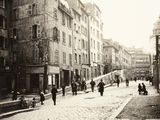 une photo en noir et blanc montrant des personnes marchant dans une rue pavée