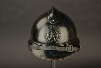 un casque en argent orné d'un lion, posé sur un socle