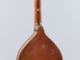 a wooden instrument hanging from a string on a white wall