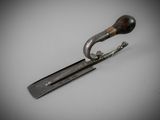 a metal object with a wooden handle on a white surface
