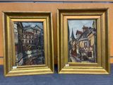 painting of a couple of buildings in a gold frame on a blue surface