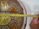 Quelqu'un mesure la hauteur d'un saladier à l'aide d'un mètre ruban.