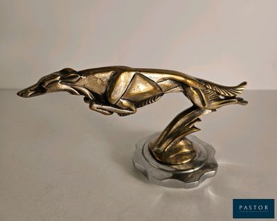statue d'un lévrier en pleine course, posée sur un socle posé sur une table