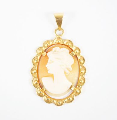 a close up of a gold plated pendant with a woman ' s profile